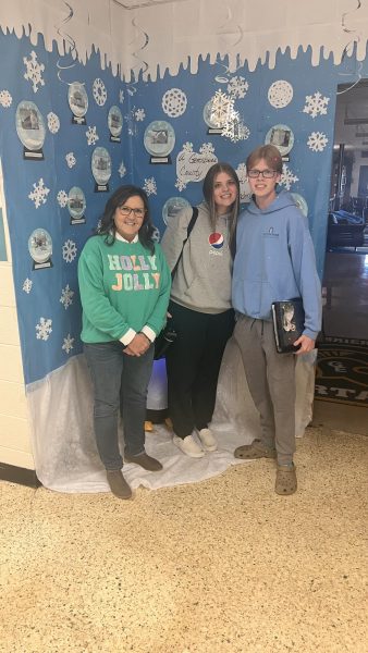 Mrs. Utterback, librarian, and seniors Kaylee Callison and Alex Vogelsong stand in front of one of the winners of the Christmas door competition. Photo by Alex Vogelsong.